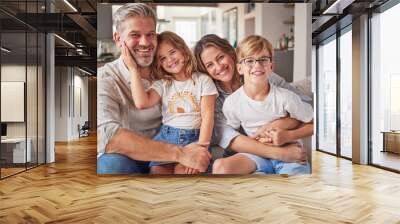 Happy, smile and portrait of a family relax in the living room bonding on the sofa together. Happiness, care and parents sitting and holding their children with love on a lounge couch at home Wall mural