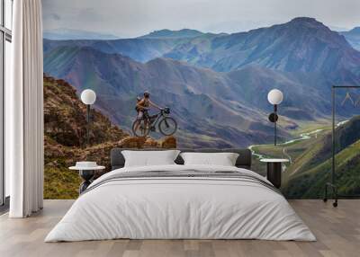 Bike trip. A man with a bicycle on a mountain pass Wall mural