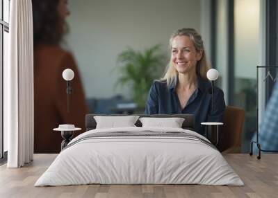 Smiling caucasian woman participates in friendly conversation in modern office setting during daytime Wall mural