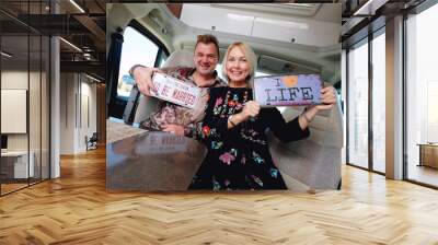 Couple sitting in camper holds hippy retro styled number plate Wall mural