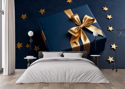 Dark blue Christmas present gift box with elegant gold bow ribbon on dark blue near stars. Greeting gift symbolize sophisticated holiday gifting. Birthday Christmas festive concept. Copy ad text space Wall mural