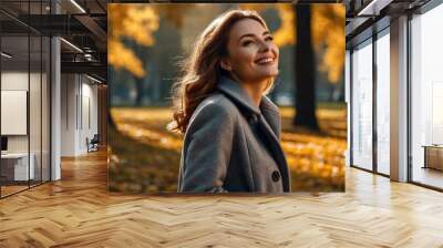 Perfect smiling lady in grey coat posing in autumn park, looking up away. Portrait of happy young woman enjoying on fresh air on September fall day. Leisure activity concept. Copy ad text space Wall mural