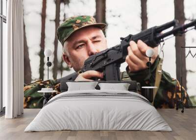 Portrait of russian soldier sniper man shoots from weapon dressed military camouflage uniform at forest nature background. Male border guard in country border holding weapon on war. Copy ad text space Wall mural