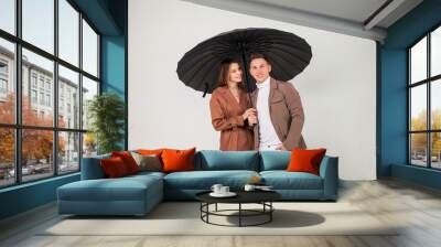 Young stylish couple with black umbrella shows love emotions Wall mural