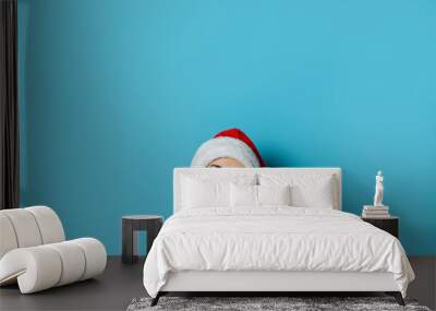 Young woman in Santa Claus hat with a mysterious face on a blue background. Concept idea for new year and christmas Wall mural