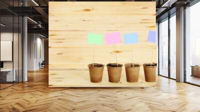 Peat pots with paper nameplates on sticks against wooden backgro Wall mural