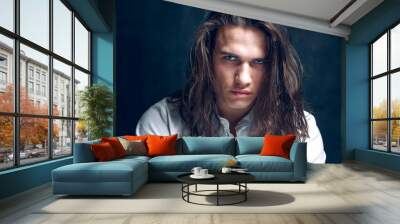 Handsome calm man. Portrait of a young muscular guy with long hair. Strong boy on an isolated dark background in the studio Wall mural