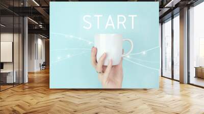 New start, beginning, business concept. Cropped view of female hand with white coffee cup and sign START Icon on blue background. Wall mural