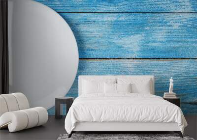 An empty round white plate on a blue wooden table. Wall mural