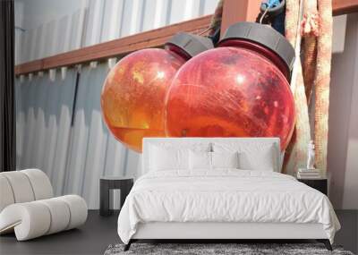 Traffic lights in a red ball shape on a fence, hanging two in the sunlight. Wall mural