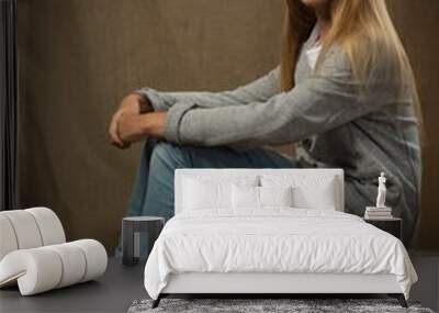 beautiful girl blonde teenager in jeans and a gray sweater sits on linen canvas Wall mural