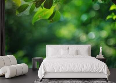 A simple wooden table with a lush green tree standing tall in the background Wall mural