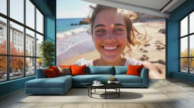 A smiling woman enjoys the sunshine on a beautiful beach with a calm blue ocean in the background Wall mural