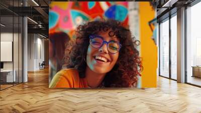 A smiling woman with curly hair and glasses, a happy expression Wall mural