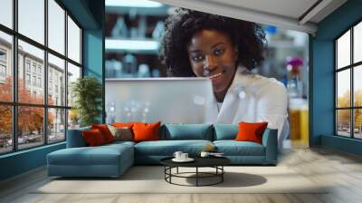 A woman sitting in front of a laptop computer, focused on her work Wall mural