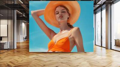 A woman wearing an orange bikini and a large hat, perfect for summer or beach-themed photoshoots Wall mural