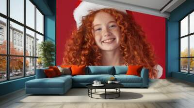 A young girl with bright red hair wearing a festive Santa hat, perfect for holiday or winter-themed projects Wall mural