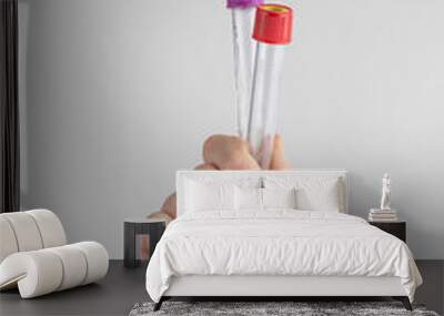 child hand holding two test tubes. white and gray background with copy space. concept of health Wall mural