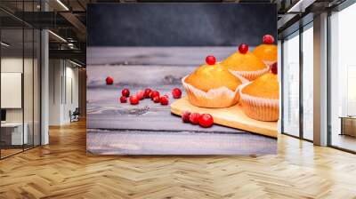 Close-up of a muffin freshly baked decorated with red berries on a light gray wooden table top on a cutting board. Wall mural