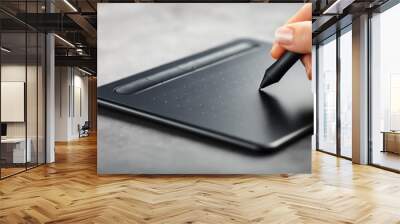 Graphic tablet with a pen in the hands of the designer, close-up. Gadget for creativity and work Wall mural