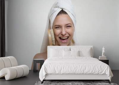 Happy lovely young girl with beautiful fresh skin and wonderful smile in a white towel posing with a spa wooden massage brush Wall mural