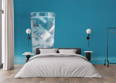 Ice cubes in a glass with crystal clear water on a blue background. Wall mural