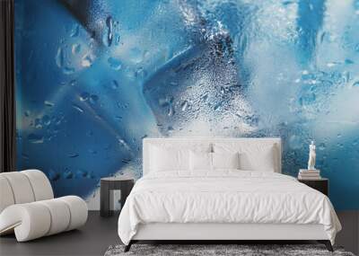 Ice cubes in a glass with refreshing ice water on a blue background. Wall mural