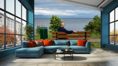 Kallaste, Estonia A man sits on a bench on the shore of Lake Peipus looking towards Russia. Wall mural