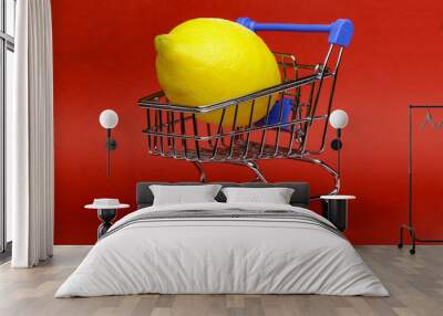 Lemon in shopping cart, shopping trolley on red background Wall mural