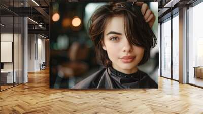 cheerful woman with short brunette hair sitting in a hairdresser's cape in a beauty salon, getting her hair cut by a professional hairdresser, beauty salon.  Wall mural