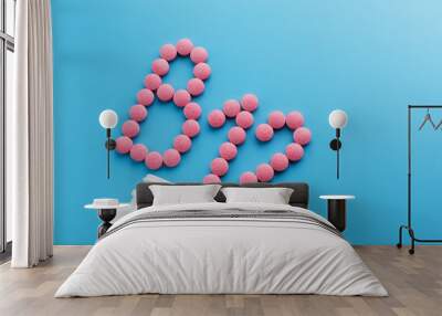 Pink pills in the shape of the letter B12 on a blue background, spilled out of a white can. Wall mural