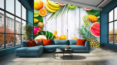 Assortment of tropical fruits with palm leaves and exotic flowers Wall mural