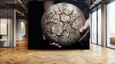 Baker's hands holding and presenting fresh baked loaf of bread Wall mural