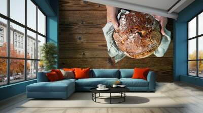 Baker's hands holding and presenting fresh baked loaf of bread Wall mural