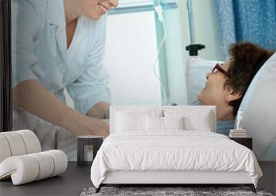 nurse cares for a female patient lying in bed in hospital Wall mural