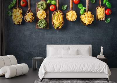 Various pasta on wooden spoons over stone background Wall mural