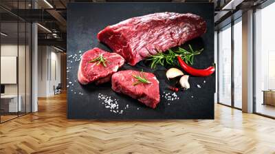 Whole piece of tenderloin with steaks and spices ready to cook on dark background Wall mural