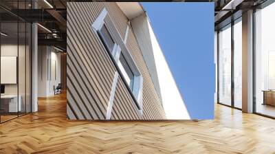 The facade of the new house clad with siding, with windows, against the blue sky. Wall mural