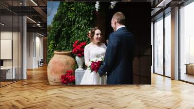 The groom in a suit and the bride in a wedding dress are standing at the wedding arch at the wedding ceremony Wall mural