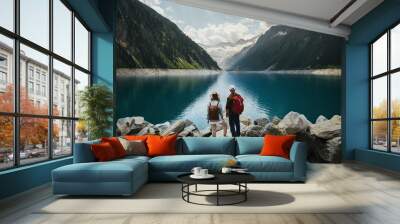 Travelers couple look at the mountain lake. People with a backpack travel. Adventure and travel in the mountains region. Zillertal Alps, Austria. Wall mural