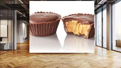 Two chocolate peanut butter cups one with a bite taken out of it on white with reflection and shadows Wall mural