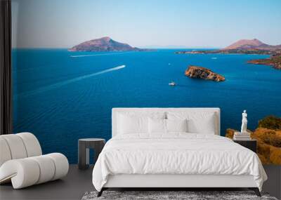 View from Cape Sounion (Greece) on Mediterranean Sea looking west with a motor boat and Patroklos island in the background and the orange sand rocks in the foreground Wall mural