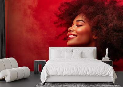 Woman with curly hair and a big smile is posing for a picture. She is wearing red lipstick and has her eyes closed. Concept of happiness and confidence Wall mural