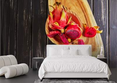 Dragon Fruit - Pitahaya Cut and one whole on a wooden stand against a black wooden background Wall mural