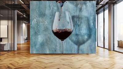 Female hands squeezing grapes into a glass with wine, on a blue background. Wine production concept. Wall mural