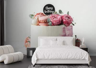 Birthday cake with white cream cheese frosting decorated with red roses and pink macaroons on the white background. Happy birthday topper on anniversary cake Wall mural