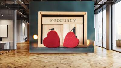 Two red hearts against the wooden calendar of blocks with the date of February 14 on the blurred dark concrete background. two red hearts with bokeh lights behind. Happy Valentine's day. Wall mural