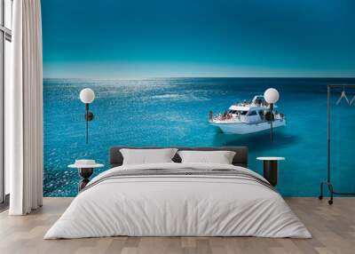 White boat with unrecognizable people in the sea with clean transparant blue water Wall mural