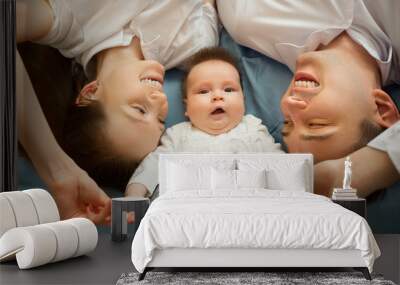 beautiful young family mom and dad lie on the bed with the little daughter at home Wall mural