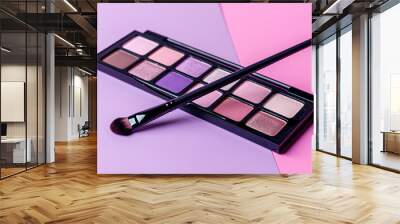 Black eyeshadow palette with brush on pink and violet background Wall mural